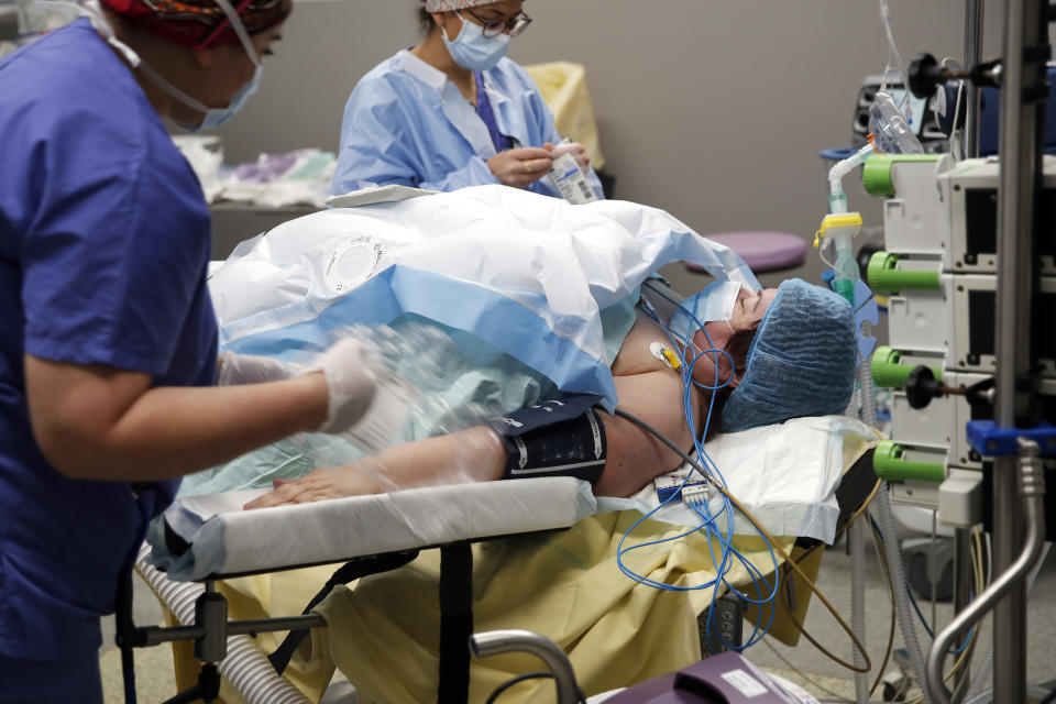 Medical staff and surgeon Lara Ribeiro Parenti, right, start the preparations for the surgery of Caroline Erganian at Bichat Hospital, AP-HP, in Paris, Wednesday, Dec. 2, 2020. Erganian, 58, hopes to shed more than a third of her weight as a result of having a large part of her stomach cut out and be free of knee and back pain — and of her cane. She prayed in the final weeks that her phone wouldn't ring with news of another delay. (AP Photo/Francois Mori)