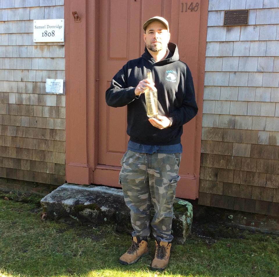 Shane Adams holds the messages in a bottle he found on a hillside while landscaping in the Port Isabella section of Cotuit. The notes may have been written by World War II German prisoners who worked in the area while being held at Camp Edwards.