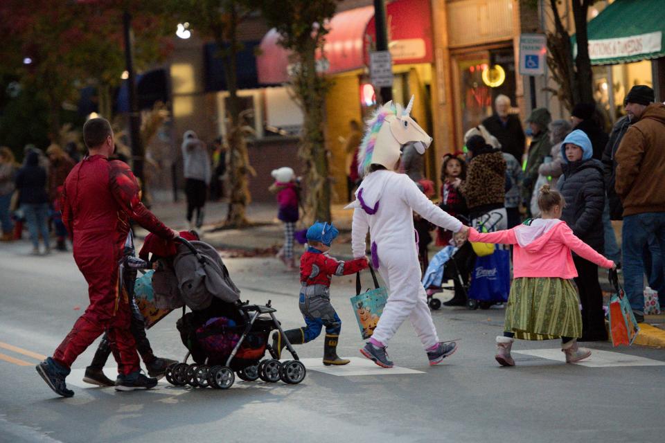 A family dressed in costume crosses Third Avenue during the Halloween parade Wednesday night in New Brighton.