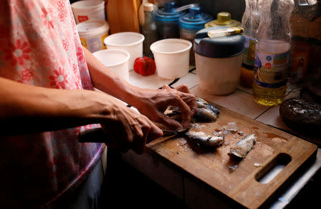 Yaneidi Guzman, 38, prepares sardines in her kitchen at home in Caracas, Venezuela, February 17, 2019. REUTERS/Carlos Garcia Rawlins