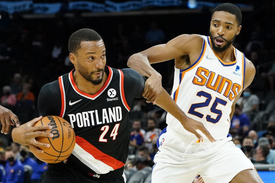 Portland Trail Blazers forward Norman Powell (24) drives as Phoenix Suns forward Mikal Bridges (25) defends during the first half of a preseason NBA basketball game, Wednesday, Oct. 13, 2021, in Phoenix. (AP Photo/Matt York)