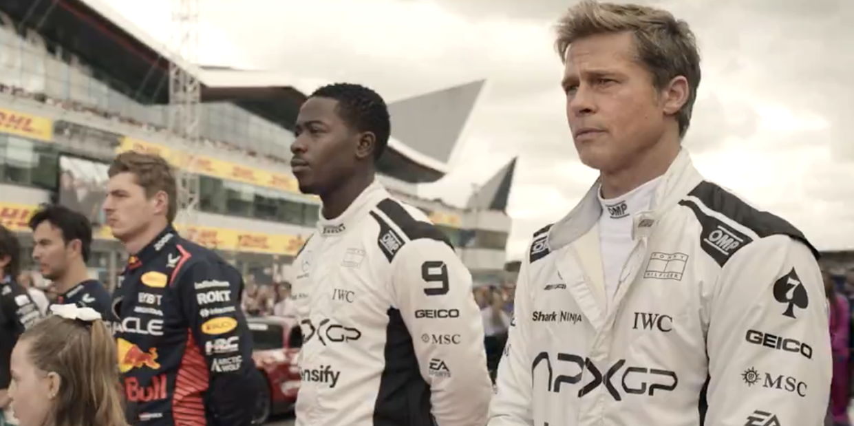 men in racing uniforms line up on track in f1