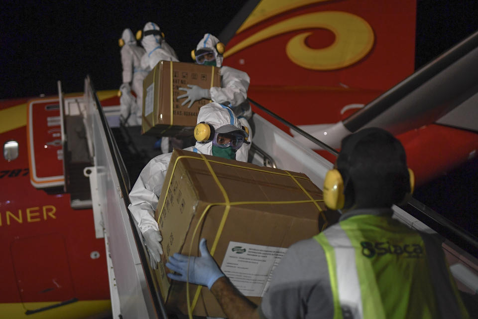 FILE - In this March 30, 2020 file photo, Venezuelan workers, wearing protective face masks and suits as a preventive measure against the spread of the new coronavirus, unload humanitarian aid from China at the Simon Bolivar International Airport in La Guaira, Venezuela. China donated more than $215 million in supplies to allies in the region, and conducted clinical trials or plans to manufacture vaccines in five countries. (AP Photo/Matias Delacroix, File)