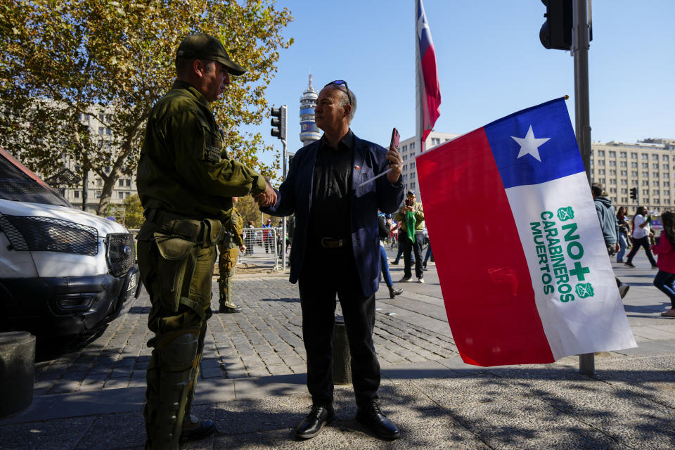 A man offers his condolences to a Chilean police officer during a demonstration seeking justice for police officers killed in the line of duty, in front of the La Moneda presidential palace in Santiago, Chile, Saturday, April 27, 2024. Three police officers were killed early Saturday, in Cañete, Chile's Bío Bío region. (AP Photo/Esteban Felix)