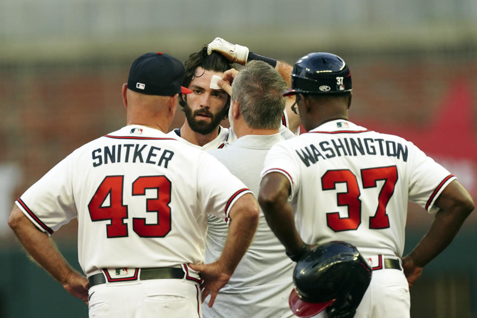 A member of the Atlanta Braves training staff tends to a small cut on Dansby Swason's forehead after he slid headfirst into second base with a double in the first inning of the team's baseball game against the New York Mets on Monday, Aug. 15, 2022, in Atlanta. Swanson stayed in the game. (AP Photo/John Bazemore)