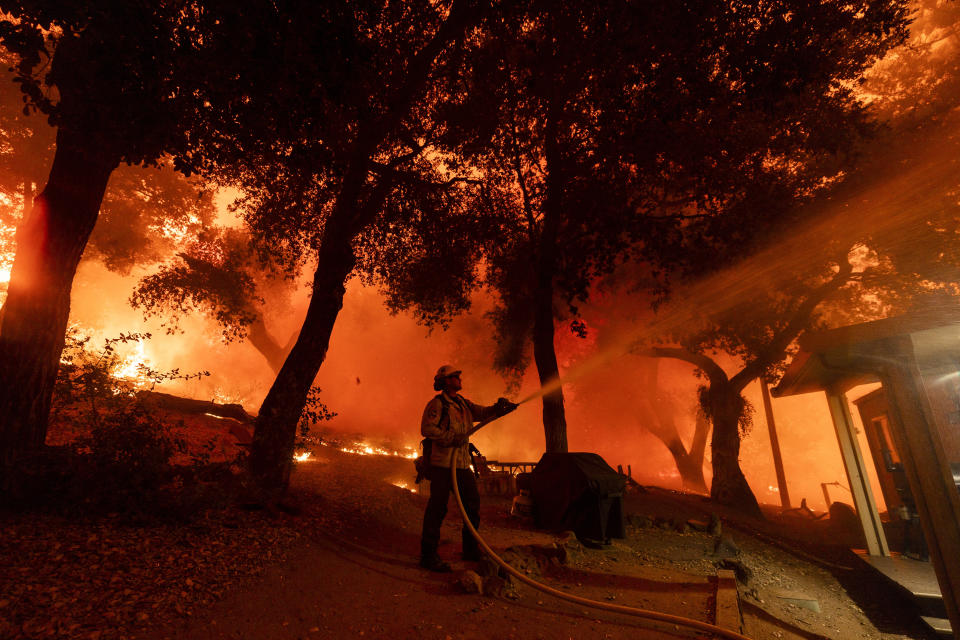 A firefighter battles the Airport Fire, Tuesday, Sept. 10, 2024, in El Cariso, an unincorporated community in Riverside County, Calif. (AP Photo/Etienne Laurent)