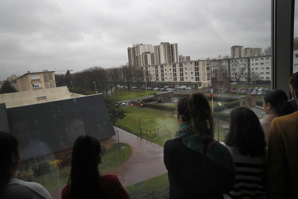 In this photo taken on Thursday Jan. 30, 2020, Students look at the Shoah memorial during a workshop dedicated to the Holocaust remembrance at the Drancy Shoah memorial, outside Paris. A French Holocaust survivor Victor Perahia was 9 when his family was seized by the Nazis, and couldn't bear to speak about what happened for 40-years, but is now telling his story to schoolchildren at Drancy, backdropped by the buildings that once imprisoned him. (AP Photo/Christophe Ena)