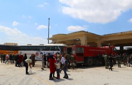 People, who were evacuated from the two rebel-besieged Shi'ite villages of al-Foua and Kefraya, stand near buses at insurgent-held al-Rashideen, Aleppo province, Syria April 19, 2017. REUTERS/Ammar Abdullah