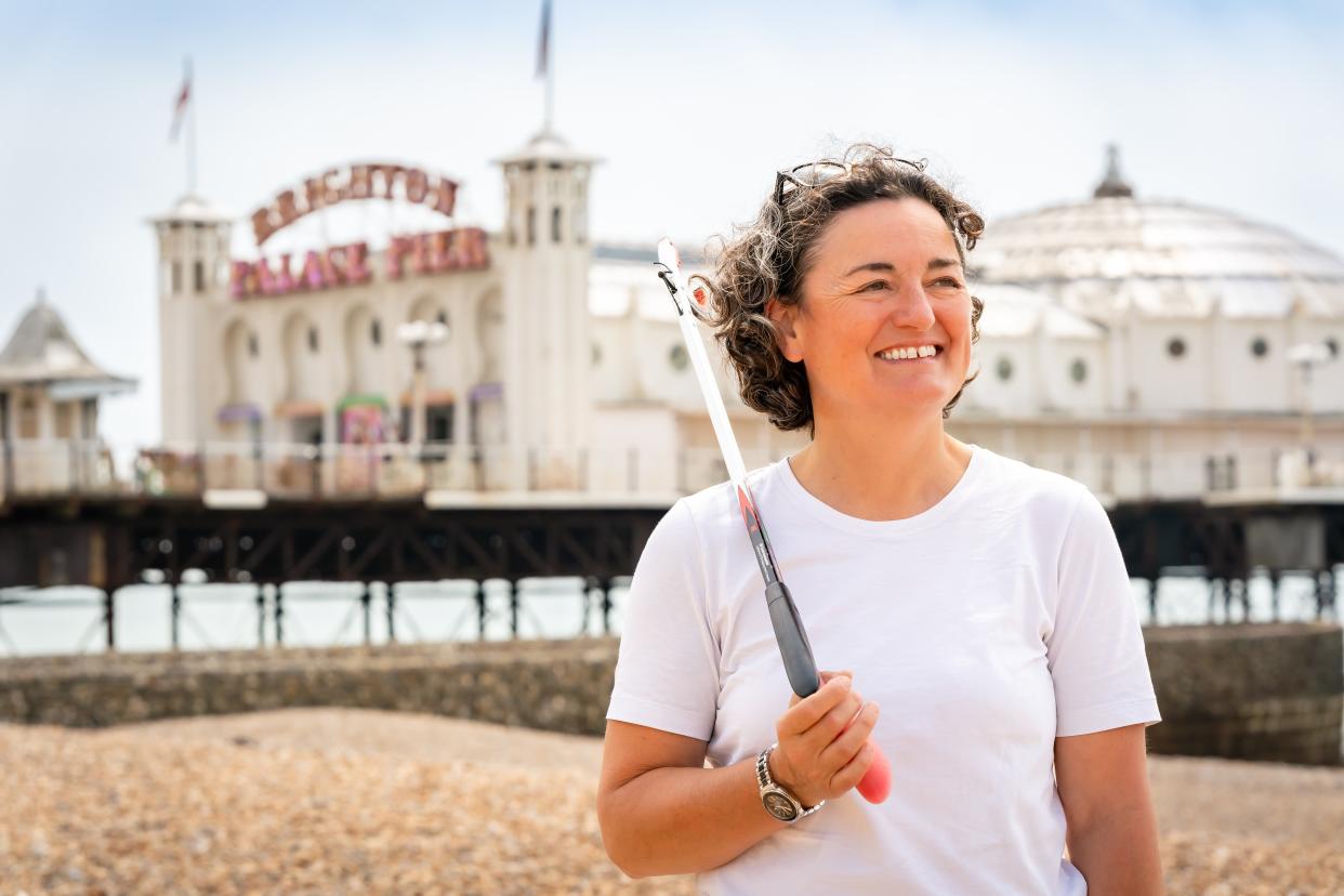 Comedian Zoe Lyons holding a litter picker in front of Brighton pier 