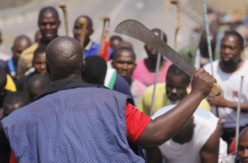 Striking mine workers armed with machetes, sticks, and spears march to a smelter plant at the Lonmin Platinum Mine near Rustenburg, Wednesday, Sept, 12, 2012 to hand over a memorandum to mine management and to ensure that workers had not reported for duty. Miners are refusing to return to work until their demands over low pay and working conditions are met. Strikes are spreading to nearby gold mines. (AP Photo/Denis Farrell)