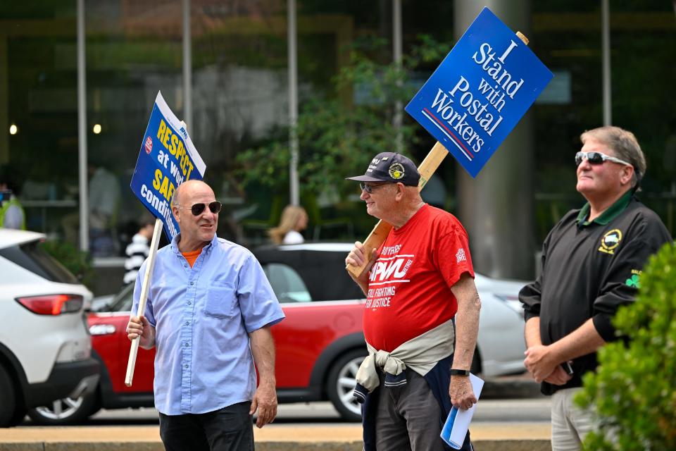 Ed Hall of Falmouth and Richard Cicchetti, center, chairman of Boston area retirees chapter, hold signs in support of postal workers during a rally Tuesday outside the U.S. Post Office in Boston.