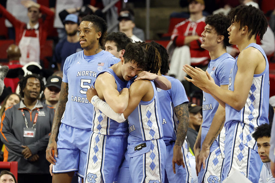 North Carolina's Cormac Ryan (3) embraces teammate RJ Davis (4) with Armando Bacot (5) nearby during the closing minutes of an NCAA college basketball game against North Carolina State in Raleigh, N.C., Wednesday, Jan. 10, 2024. (AP Photo/Karl B DeBlaker)