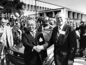 FILE - In this April 13, 1985 file photo, then Toyota Motor Corp. Chairman Eiji Toyoda, left, and then General Motors Corp. Chairman Roger B. Smith shake hands in front of a Chevrolet Nova as the new United Motor Manufacturing Inc., was inaugurated with a dedication ceremony at the Fremont, Calif., plant. The 50-50 joint-venture plant in Fremont, between Toyota Motor Corp. and U.S. automaker General Motors Co. started rolling out cars in 1984 and was heralded as a pioneer in international collaboration. (AP photo/Paul Sakuma, File)