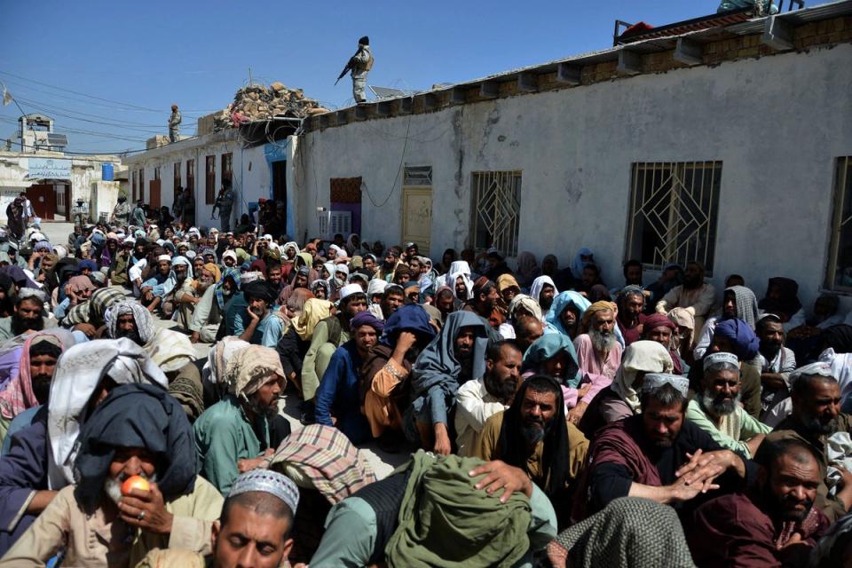 A Taliban soldier stands guard on a roof as men imprisoned for drug use sit in a courtyard before their release from Kandahar Central Prison (AFP via Getty)