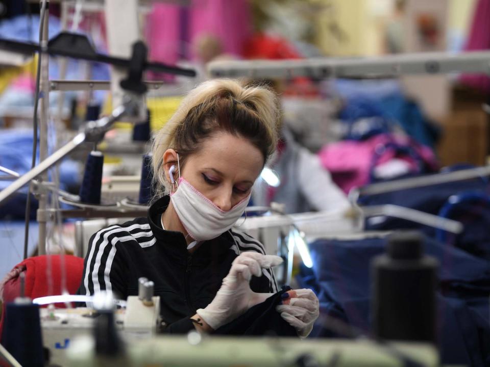 A worker makes scrubs for NHS at the Fashion Enter factory in London on 7 April 2020. The factory normally creates clothes for Asos: EPA