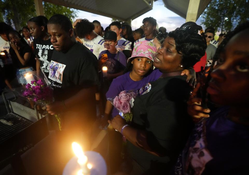 Omega McDaniels, left, and Tonisha Johnson, the parents of Christopher Hampton, join family and friends as they hold a vigil for their son, a 15-year-old Cesar Chavez High School football player who was found dead in Show Low Lake.