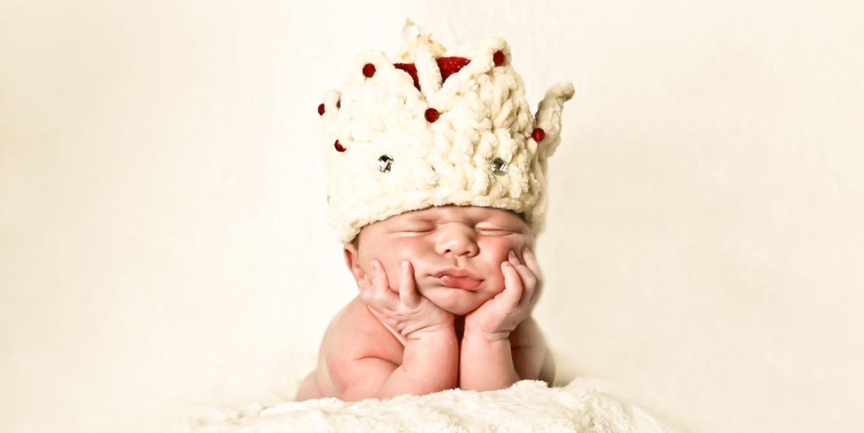 newborn baby wearing a crown sleeping on his hands