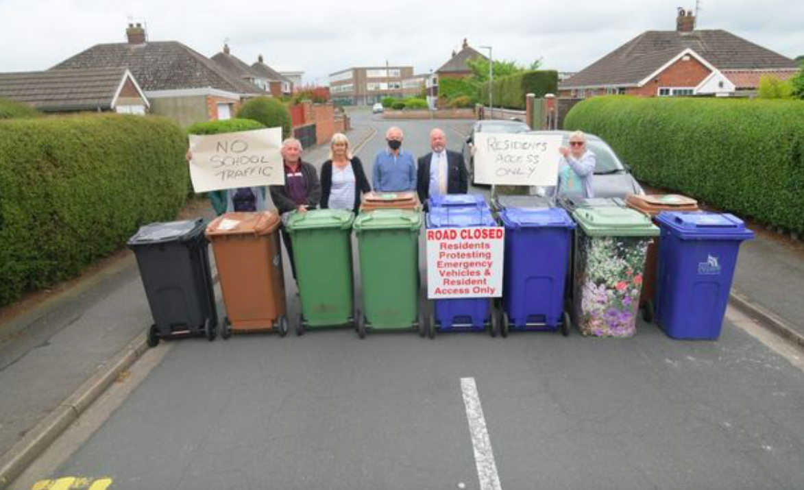 Residents set up a barricade using wheelie bins in protest at their road continuously being used by parents during school-run times. (Reach)