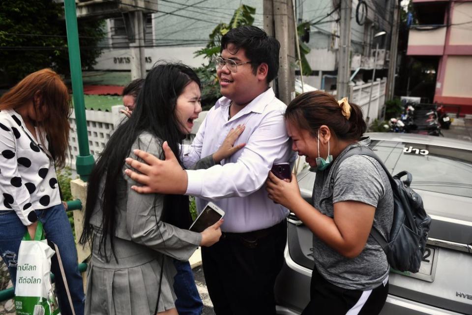 Activist Bunkueanun "Francis" Paothong (C) comforts loved ones before he enters the Dusit Police Station to answer charges of harming Thailand's Queen Suthida in Bangkok on Oct. 16, 2020.<span class="copyright">Lillian SUWANRUMPHA—AFP/Getty Images</span>