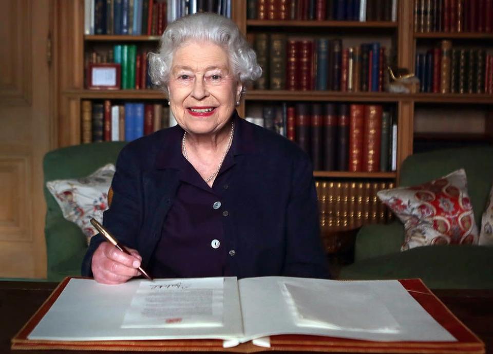 La reina firmando un documento