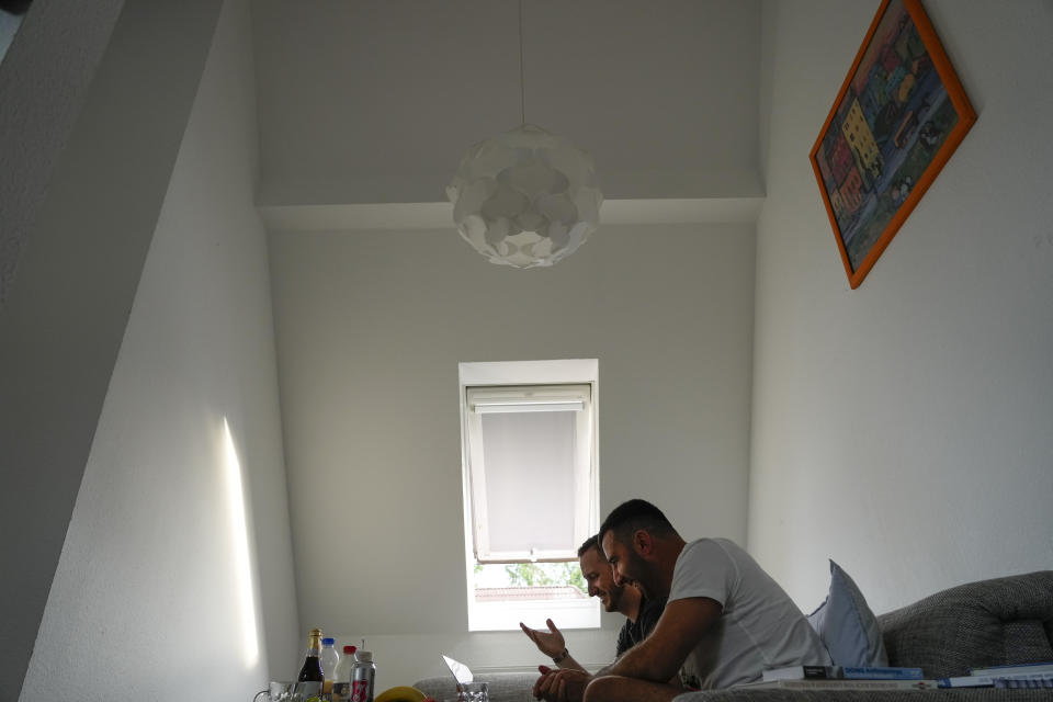 U.S. Army veteran Spencer Sullivan, left, and Abdulhaq Sodais, who served as his translator in Afghanistan, center, talk when looking at images taken in Afghanistan, at Sodais' apartment in Bremen, Germany, Friday, Aug. 13, 2021. Sullivan is trying to help Sodais get asylum after he had to flee to Germany. (AP Photo/Peter Dejong)