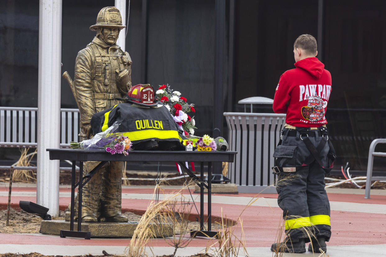 A fellow firefighter stands in front of a memorial set up for volunteer firefighter Lt. Ethan Quillen outside the Paw Paw fire department in Paw Paw, Mich. on Thursday, Feb. 23, 2023. Quillen died after coming into contact with a downed power line in Almena Township. (Joel Bissell/Kalamazoo Gazette via AP)