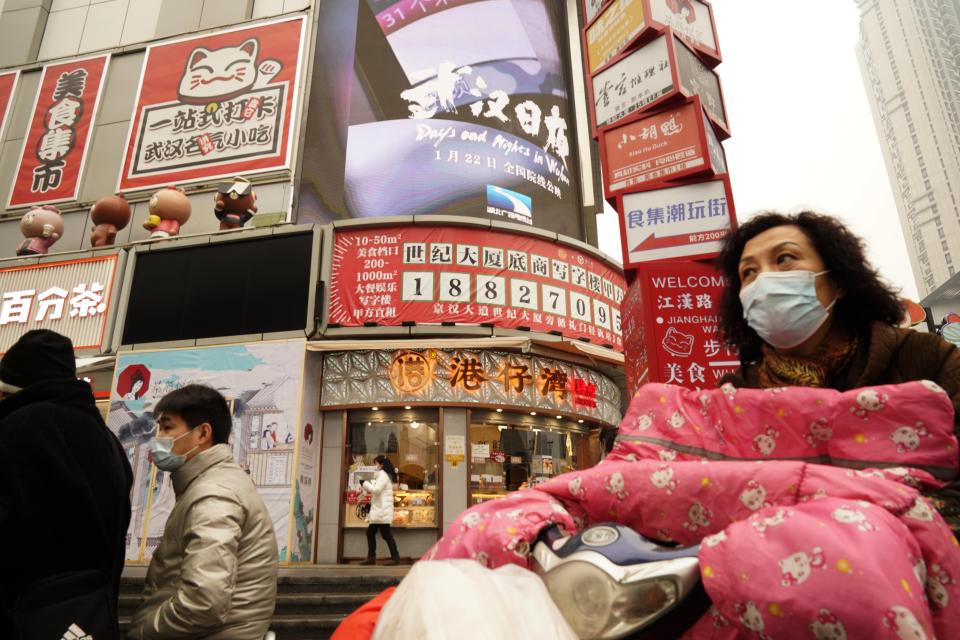 Residents wearing masks past by a screen showing a trailer for the film "Days and Nights in Wuhan" outside a mall in Wuhan in central China's Hubei province on Friday, Jan. 22, 2021. China is rolling out the state-backed film praising Wuhan ahead of the anniversary of the 76-day lockdown in the central Chinese city where the coronavirus was first detected. (AP Photo/Ng Han Guan)