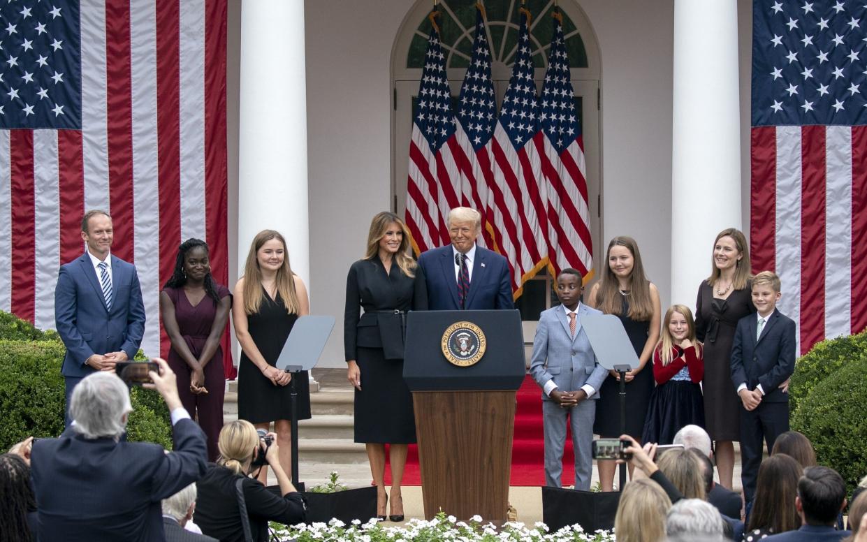 U.S. President Donald Trump, center, First Lady Melania Trump, left center, Supreme Court Justice nominee Amy Coney Barrett, second right, and her family stand on stage following a ceremony in the Rose Garde - Bloomberg 