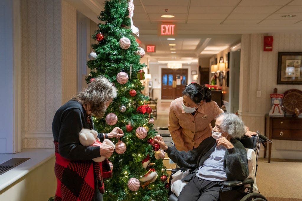 Tina Sandri, CEO of Forest Hills of DC senior living facility, center, greets residents Cherie Neville, left, and Catherine Doleman on Thursday, Dec. 8, 2022, in Washington. As nursing home leaders redouble efforts to get staff and residents boosted with the new vaccine version, now recommended for those 6 months and older, they face complacency, misinformation and COVID-19 fatigue.