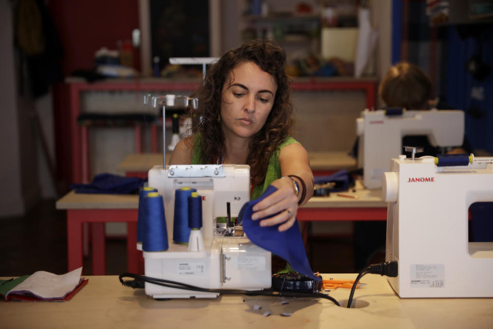 Textile artist Brooke Dennis, who is originally from New Zealand, makes scrubs for NHS (National Health Service) staff to wear during the coronavirus outbreak, at her textiles and craft studio called Make Town, in east London, Thursday, April 23, 2020, as part of the Scrub Hub network of voluntary community groups. The Scrub Hub just wanted to help, but they created a movement with some 70 hubs employing the skills of more than 2,200 volunteers all over the nation responding to the coronavirus pandemic, with a template for PPE, a pattern that so far has made more than 3,800 sets of scrubs for healthcare workers. (AP Photo/Matt Dunham)