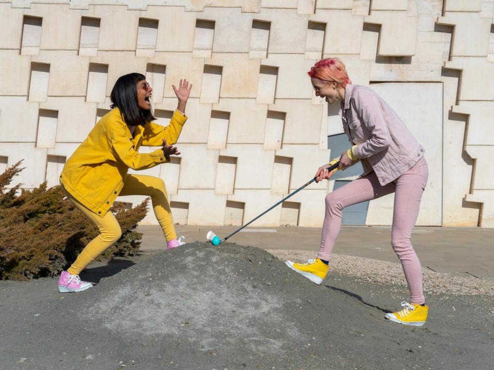 Two women play mini golf.