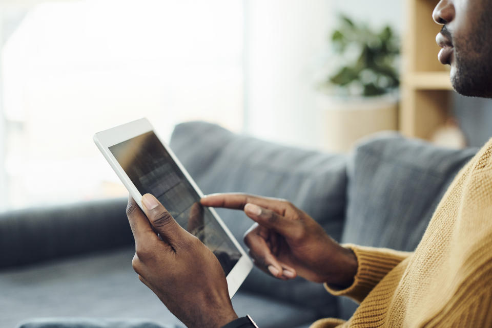 Shot of a young man using a digital tablet while relaxing at home