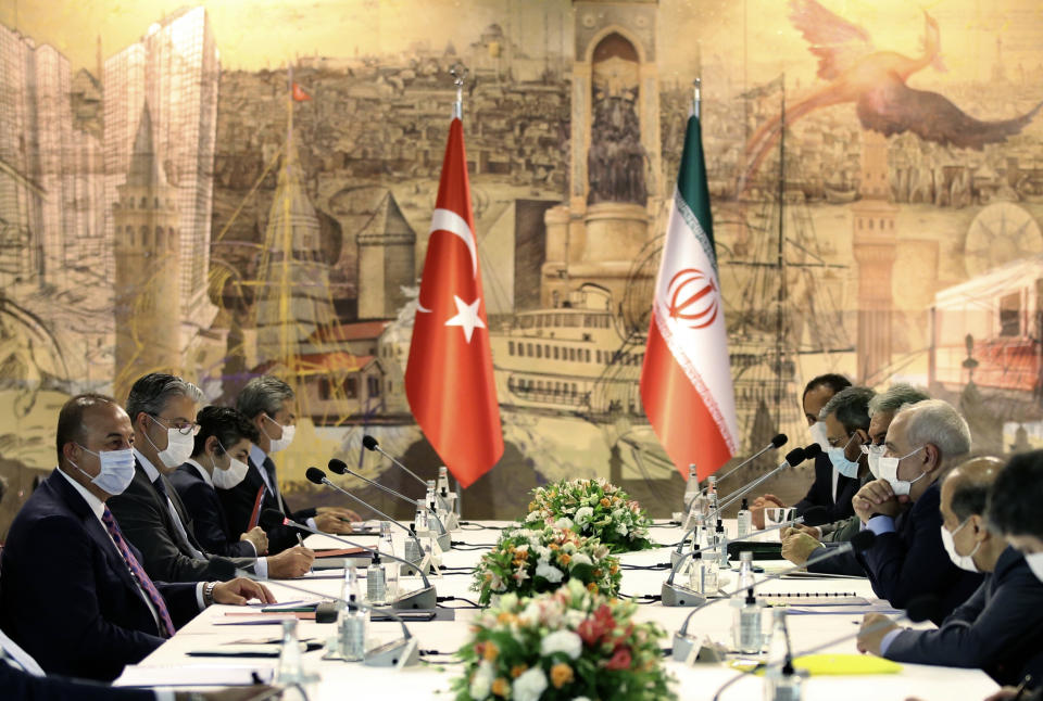 Turkish Foreign Minister Mevlut Cavusoglu, left, and Iran's Foreign Minister Mohammad Javad Zarif, second right, wearing face masks to protect against the coronavirus, speak during a meeting, in Istanbul, Monday, June 15, 2020. The two discussed the bilateral issues and Syria. (Turkish Foreign Ministry via AP, Pool)