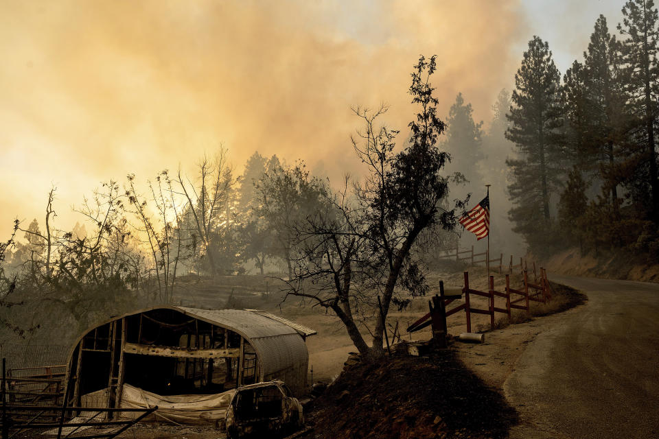 A flag flies behind a scorched outbuilding as the Mosquito Fire burns along Michigan Bluff Rd. in unincorporated Placer County, Calif., on Wednesday, Sept. 7, 2022. (AP Photo/Noah Berger)