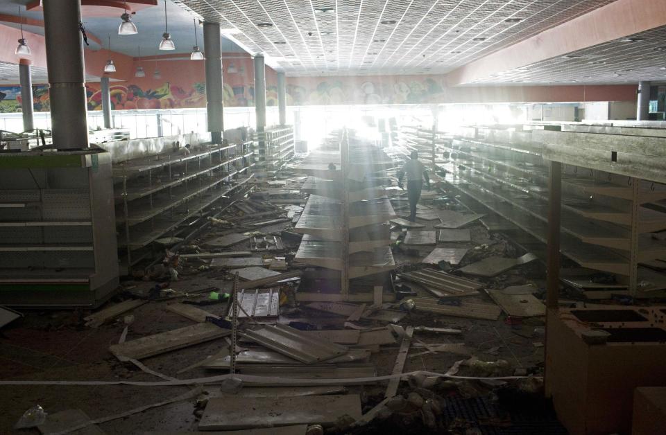 A worker walks inside a looted supermarket at the SuperLider commercial center in Maracay, Venezuela, Wednesday, Feb. 26, 2014. People looted the commercial center on Monday night, after almost two weeks of protests that began with students and were joined by others in several cities, upset over crime, economic problems and the heavy-handed government response to the protests. (AP Photo/Rodrigo Abd)