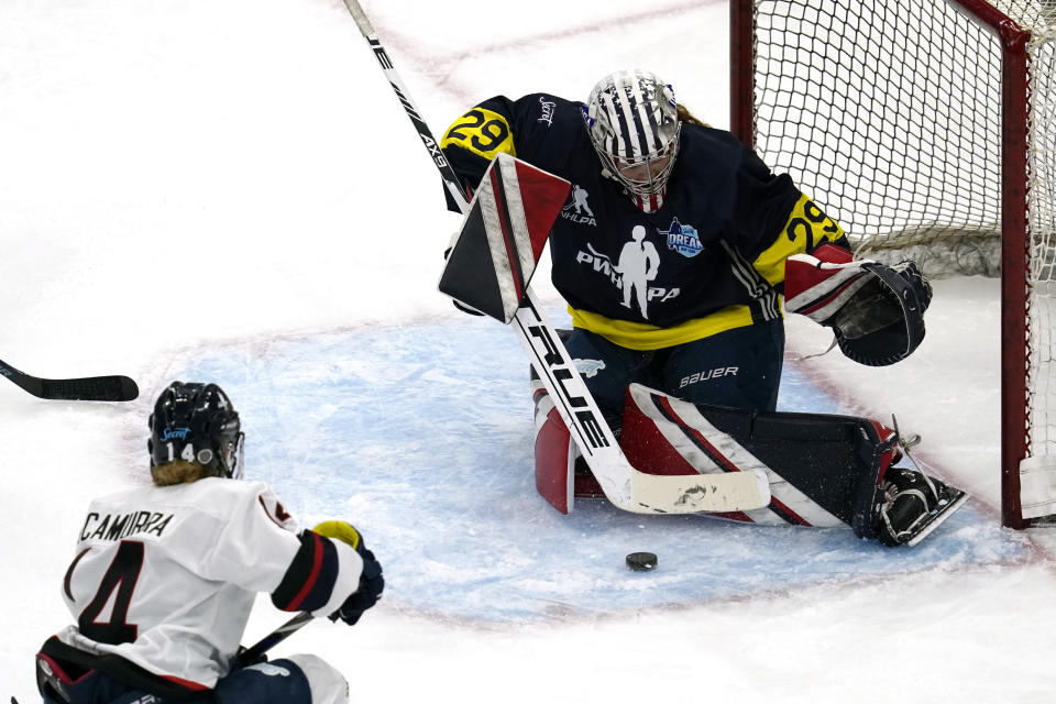 FILE- Team Adidas Minnesota goalie Nicole Hensley, right, makes a save on a shot by Women's Sports Foundation New Hampshire's Hayley Scamurra during the third period of the Dream Gap Tour hockey game at the United Center in Chicago, on March 6, 2021. The Professional Women’s Hockey Players’ Association is resuming its Dream Gap barnstorming tour for a fourth consecutive year, while still developing plans to launch a professional league. (AP Photo/Nam Y. Huh, File)