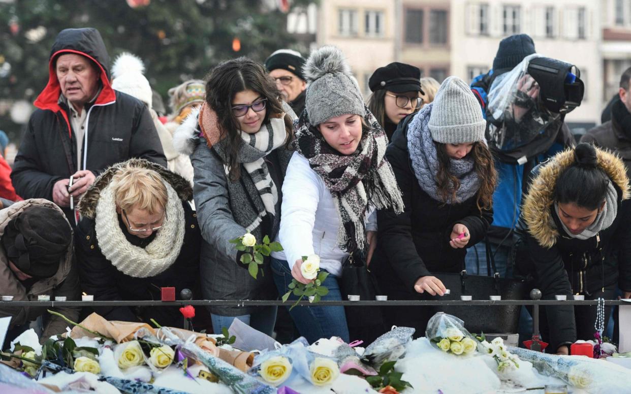 People light-up candles and deposit flowers during a gathering around a makeshift memorial  - AFP