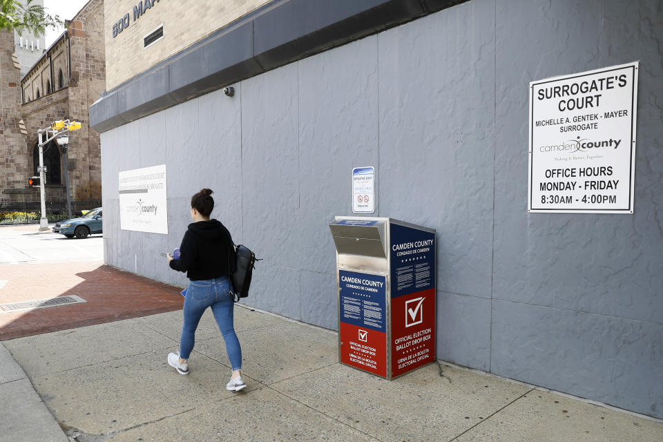 FILE - In this July 1, 2020, file photo, a woman walks past a vote-by-mail drop box for the upcoming New Jersey primary election outside the Camden, N.J., Administration Building. Democrats plan to move quickly on one of the first bills of the new Congress, which would set federal election standards. The For the People Act would require states to offer early voting, same-day registration and the option of absentee voting for all registered voters. (AP Photo/Matt Slocum, File)