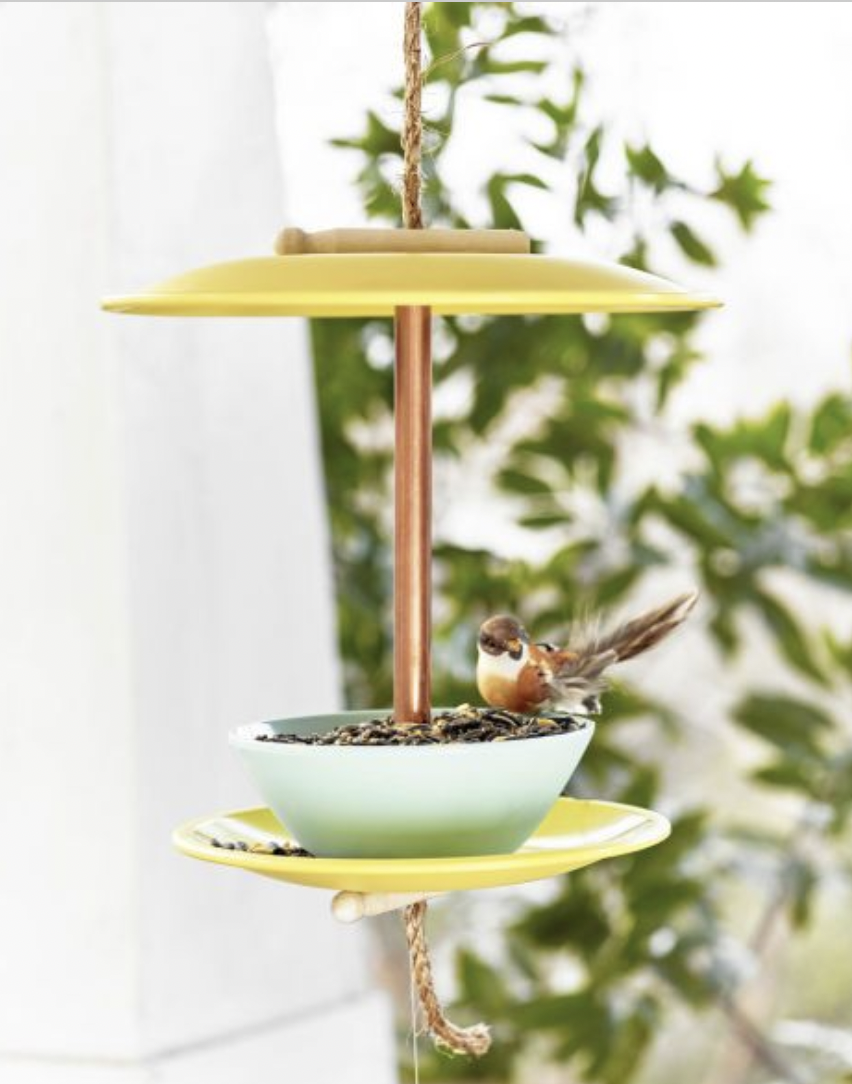 a bird feeder made from yellow and blue melamine plates and blows hung on a front porch