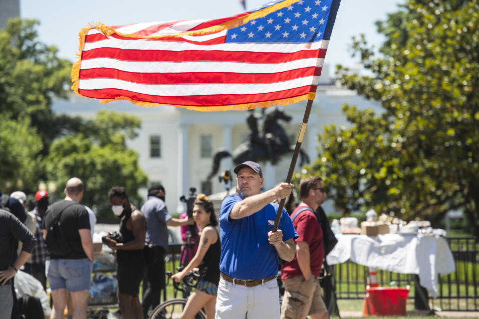 Un hombre hondea una bandera de Estados Unidos delante de la Casa Blanca. (Foto: Tom Williams/CQ-Roll Call, Inc via Getty Images)