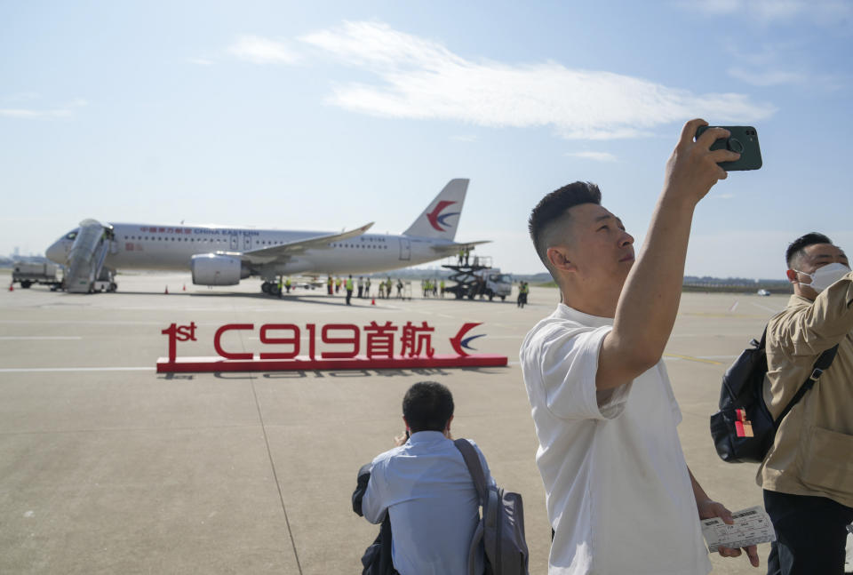 In this photo released by Xinhua News Agency, a passenger takes a selfie near a sign which reads "1st C919 inaugural flight" displayed in front of the Chinese made passenger aircraft prepared for its first commercial flight from Shanghai on Sunday, May 28, 2023. China’s first domestically made passenger jet flew its maiden commercial flight on Sunday, as China looks to compete with companies such as Boeing and Airbus in the global aircraft market.(Ding Ting/Xinhua via AP)