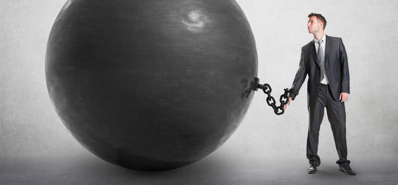 A man is shackled to a giant black ball.