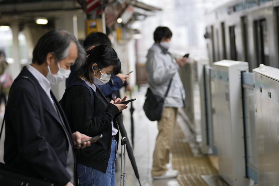 People wearing face masks wait for a ride as the train approaches the platform of a station in Tokyo, Friday, April 15, 2022. (AP Photo/Hiro Komae)