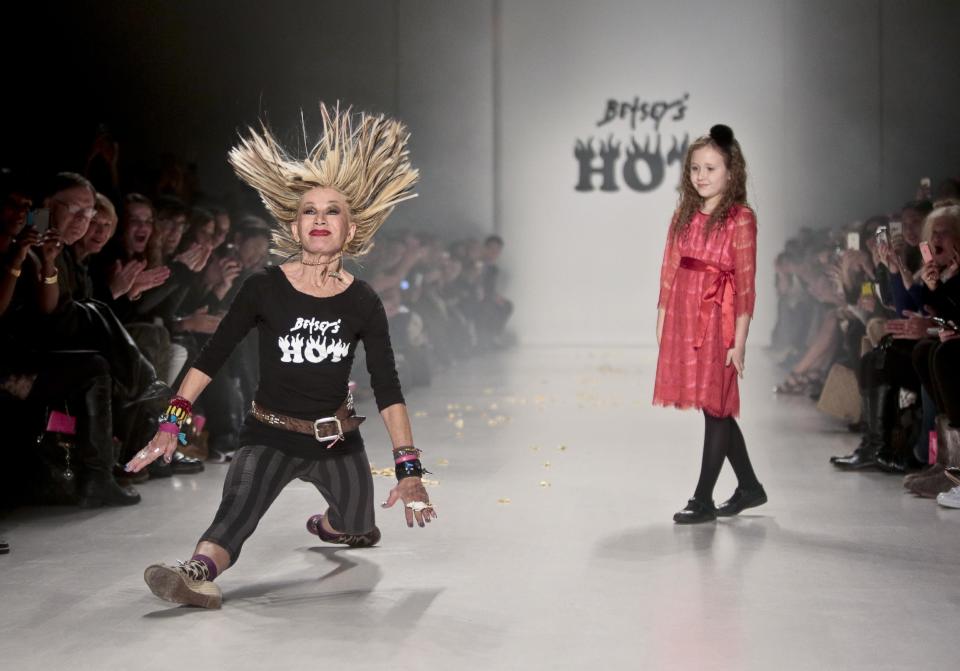 Fashion designer Betsey Johnson lands into a split while doing acrobatics on the runway as her granddaughter looks on after showing her Fall 2014 collection, during New York Fashion Week on Wednesday Feb. 12, 2014. (AP Photo/Bebeto Matthews)