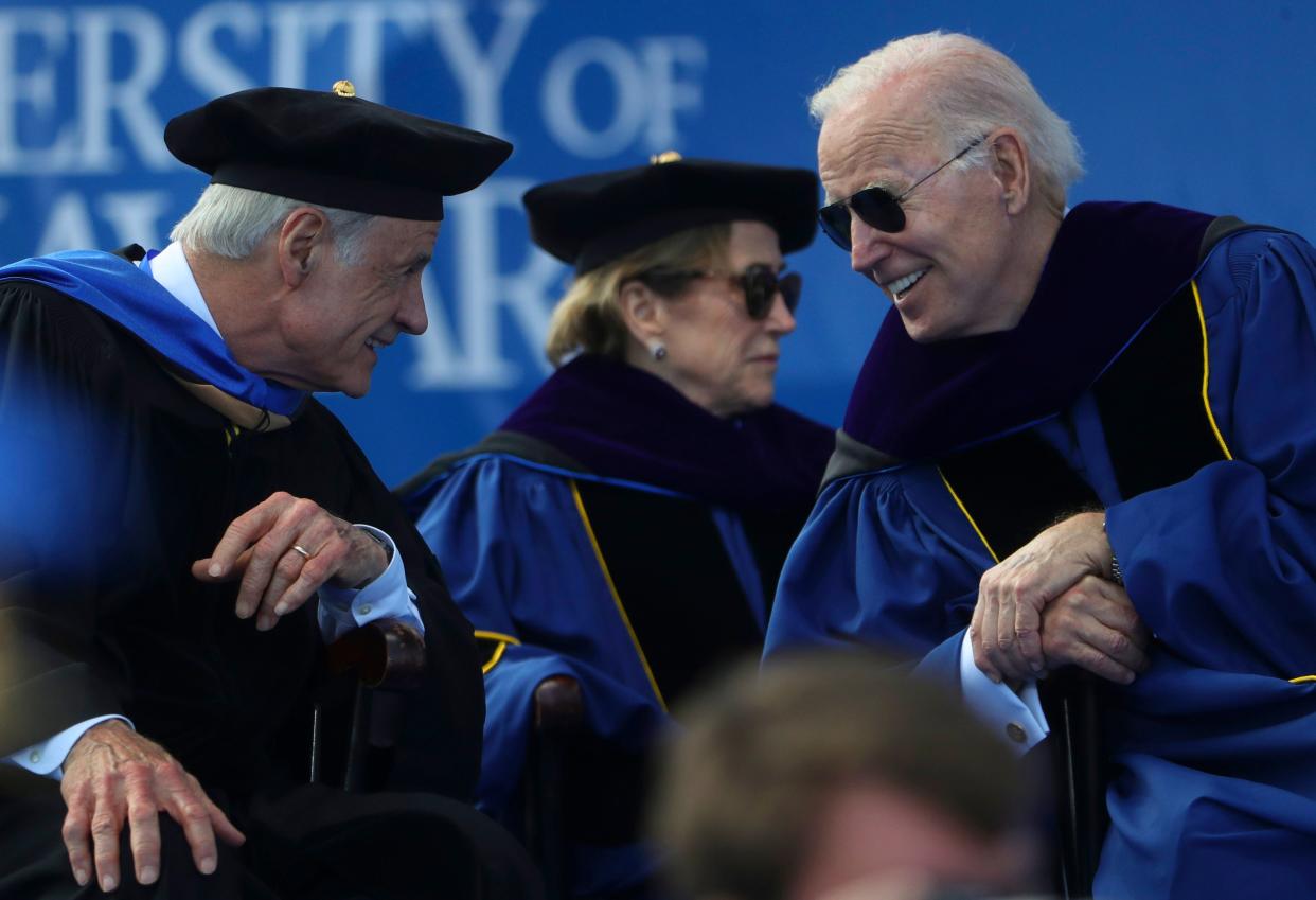 Senator Tom Carper (left) and President Joe Biden share a laugh at the start of the University of Delaware's 2022 Commencement at Delaware Stadium, Saturday, May 28, 2022. Biden's sister, Valerie Biden Owens, sits behind them.