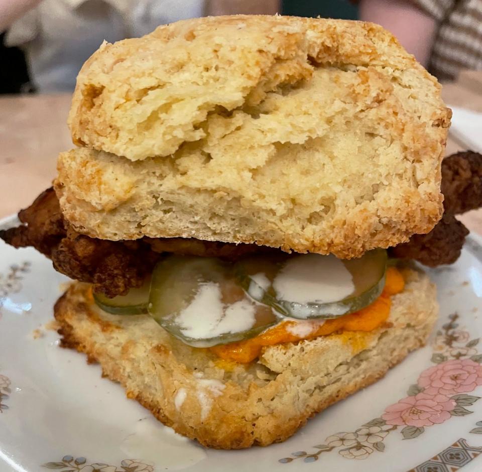 Fried chicken biscuit sandwich with pickles and sauce on a floral plate