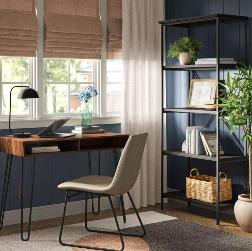 A home office setup with a desk, chair, laptop, bookshelf, and decorative plants