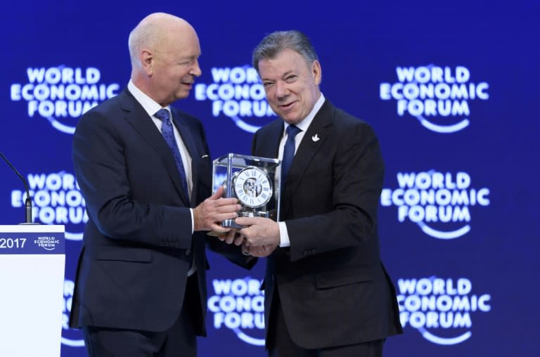 Colombian President Juan Manuel Santos (R) receives a prize from World Economic founder and executive chairman Klaus Schwab during a session at the Congress hall on the second day of the World Economic Forum, on January 18, 2017 in Davos