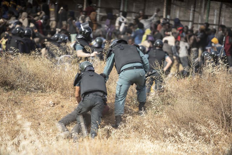 Un migrante es detenido por agentes de policía en suelo español tras cruzar las vallas que separan el enclave español de Melilla de Marruecos en Melilla, España, el viernes 24 de junio de 2022. Decenas de migrantes asaltaron el viernes el paso fronterizo entre Marruecos y la ciudad enclave española de Melilla en lo que es la primera incursión de este tipo desde que España y Marruecos arreglaron sus relaciones diplomáticas el mes pasado.