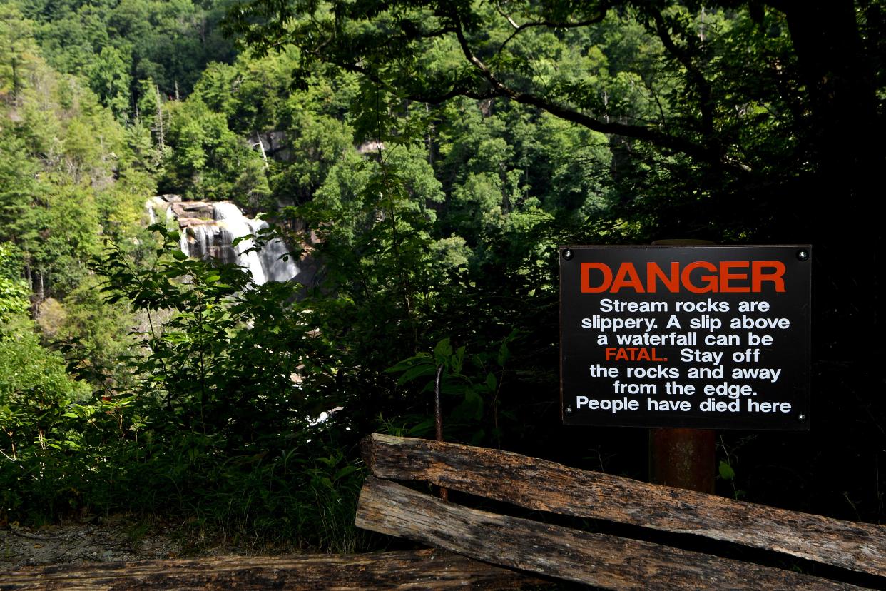 A sign at an observation point uses blunt language at White Water Falls in the Nantahala National Forest on Wednesday, July 25, 2018. The waterfall is the highest in the East at more than 400 feet. It is also one of the most deadly. A least 13 people have died at the falls since 1995. 